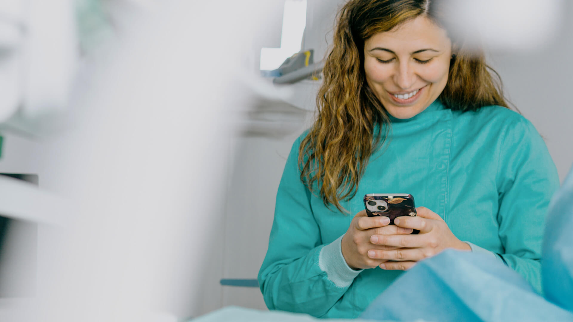 A dentist is smiling and using her phone inside her dental clinic.